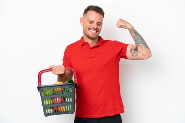 Beyaz arka planda izole edilmiş bir sepet dolusu yiyecek taşıyan beyaz bir adam güçlü bir hareket yapıyor.