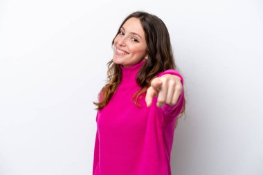 Beyaz arka planda izole genç beyaz kadın mutlu bir ifadeyle ön tarafı işaret ediyor.