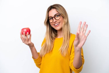 Uruguaylı genç bir kadın, beyaz arka planda izole edilmiş, mutlu bir ifadeyle selamlıyor.