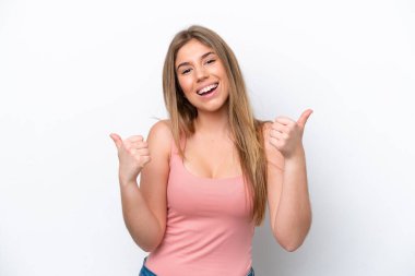 Beyaz fırında izole edilmiş genç beyaz bir kadın. Baş parmakları havada ve gülümsüyor.