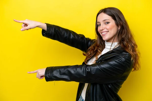 黄色の背景に指を向け製品を提示する若い白人女性 — ストック写真
