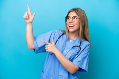 Young surgeon doctor woman isolated on blue background pointing with the index finger a great idea