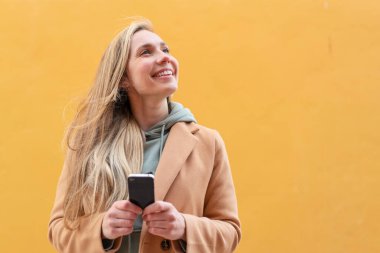 Açık havada cep telefonu kullanan genç sarışın bir kadın.