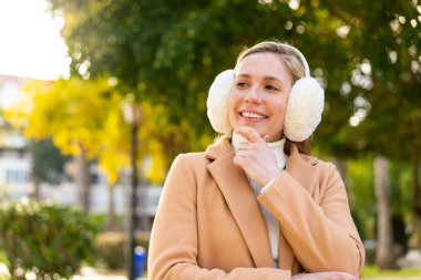 Sarışın genç bir kadın açık havada kışlık manşetler takıyor.