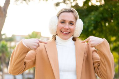 Açık havada kışın kuklalar takan genç sarışın kadın gururlu ve kendini beğenmiş.