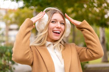 Sarışın, güzel bir kadın. Açık havada kışlık manşetler takıyor. Sürpriz bir ifadeyle.