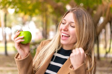 Dışarıda elmalı güzel sarışın bir kadın zaferi kutluyor.