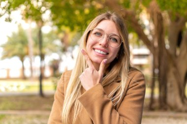 Açık havada gülümseyen güzel sarışın kadın.