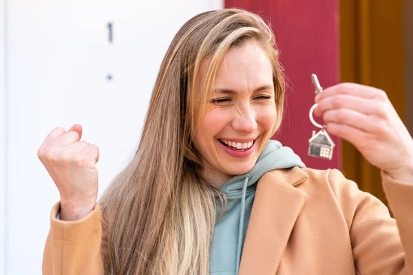 年轻的金发女子在户外拿着家里的钥匙庆祝胜利 — 图库照片