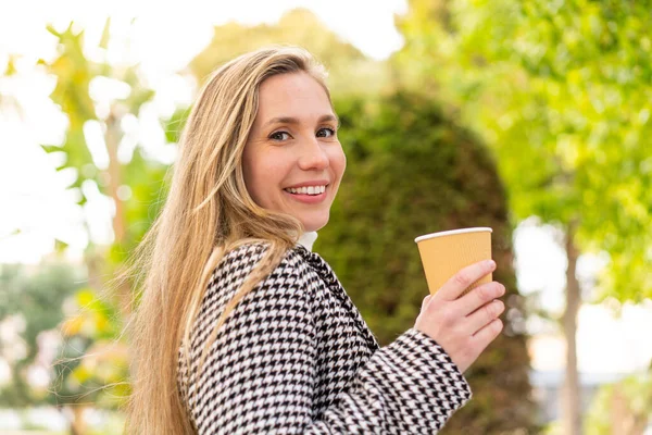 年轻的金发女人在户外拿着咖啡 — 图库照片