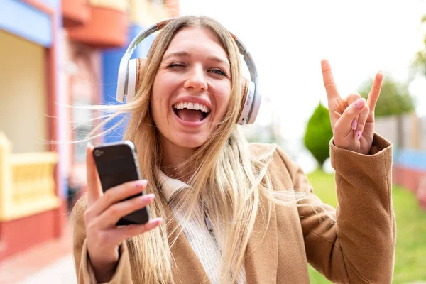 Молодая Красивая Блондинка Открытом Воздухе Слушает Музыку Помощью Мобильного Жеста — стоковое фото