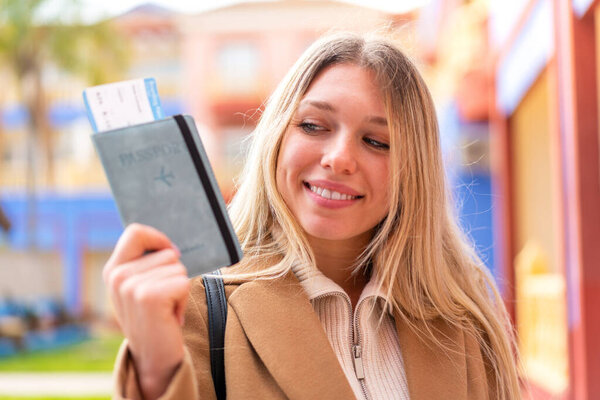 Young pretty blonde woman holding a passport at outdoors