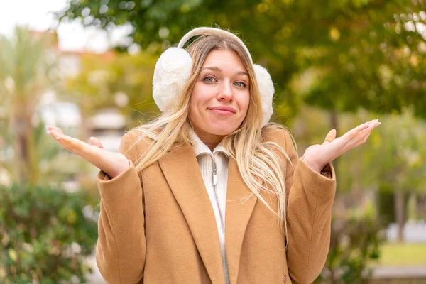Young Pretty Blonde Woman Wearing Winter Muffs Outdoors Having Doubts — Stock Photo, Image