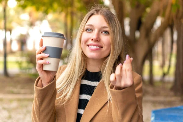 年轻漂亮的金发女人在户外端着咖啡 — 图库照片
