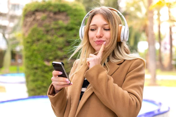 Νεαρή Όμορφη Ξανθιά Γυναίκα Ακούει Μουσική Ακουστικά Εξωτερικούς Χώρους Σκέψης — Φωτογραφία Αρχείου