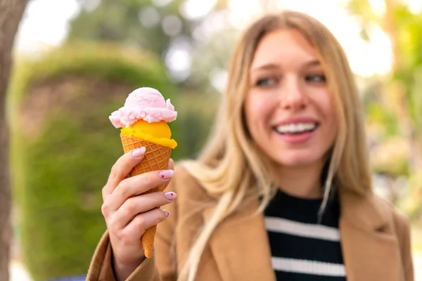 Stock image Young pretty blonde woman with a cornet ice cream at outdoors