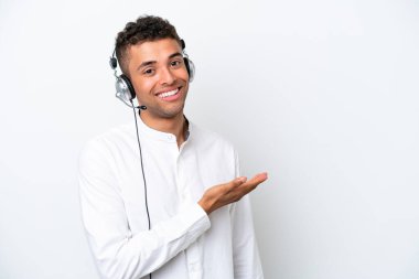 Tele pazarlamacı Brezilyalı bir adam beyaz arka planda izole edilmiş bir kulaklıkla çalışırken bir fikir sunuyor ve gülümsüyor.