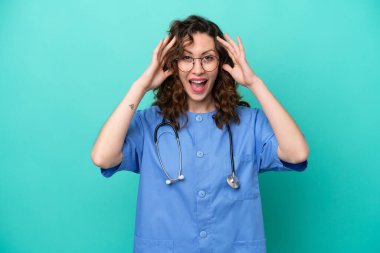 Genç beyaz kadın, mavi arka planda izole edilmiş, sürpriz bir ifadeyle.