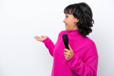 Genç Arjantinli şarkıcı kadın, beyaz arka planda sürpriz bir ifadeyle tek başına bakarken,