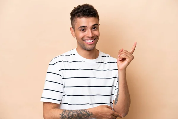 Mladý Brazilský Muž Izolovaný Béžovém Pozadí Šťastný Ukazuje Nahoru — Stock fotografie