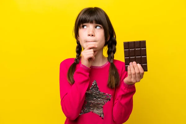 Malá Kavkazská Dívka Čokoládou Izolované Žlutém Pozadí Mají Pochybnosti Myšlení — Stock fotografie