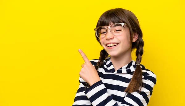 stock image Little caucasian girl isolated on yellow background With glasses and pointing side