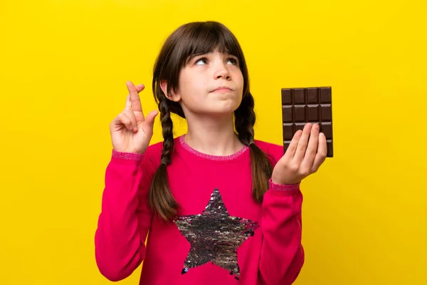 Malá Kavkazská Dívka Čokoládou Izolované Žlutém Pozadí Prsty Kříž Přeje — Stock fotografie