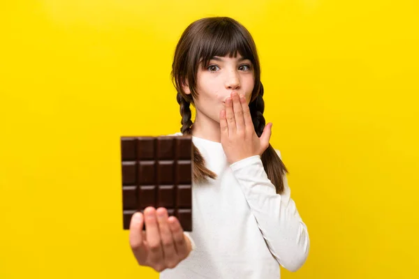 Little Caucasian Girl Isolated Yellow Background Taking Chocolate Tablet Surprised — Stock fotografie