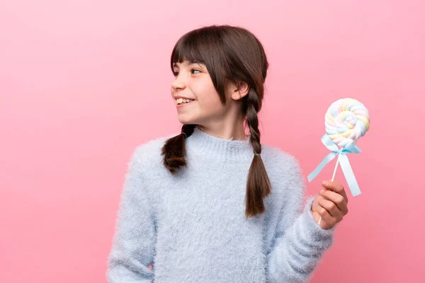 stock image Little caucasian girl holding a lollipop looking to the side and smiling