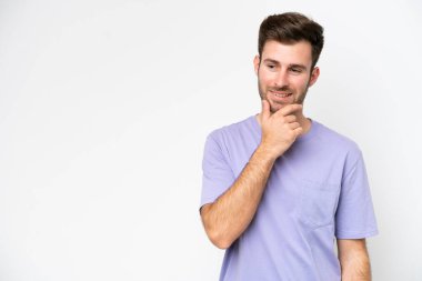 Beyaz arka planda izole edilmiş genç beyaz adam yana bakıyor ve gülümsüyor.