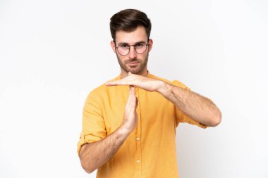 Beyaz arka planda izole edilmiş genç beyaz bir adam zaman aşımı hareketi yapıyor.