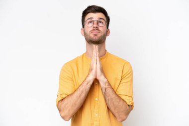 Beyaz arka planda izole genç beyaz adam avuç içlerini bir arada tutuyor. İnsan bir şey ister.