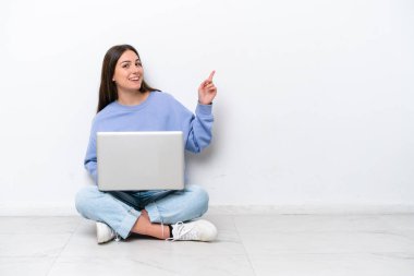 Dizüstü bilgisayarı olan beyaz arka planda izole bir şekilde oturan beyaz saçlı genç bir kadın.