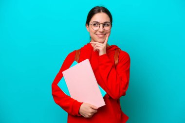 Young student caucasian woman isolated on blue background thinking an idea while looking up