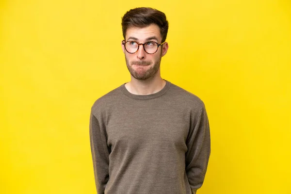 Young Caucasian Man Isolated Yellow Background Having Doubts While Looking — Stock Photo, Image