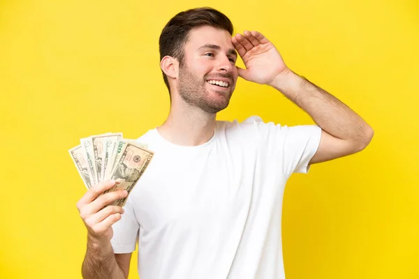 Jonge Kaukasische Man Neemt Veel Geld Geïsoleerd Gele Achtergrond Glimlachen — Stockfoto