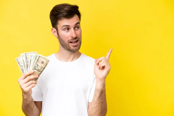 Joven Hombre Caucásico Tomando Montón Dinero Aislado Sobre Fondo Amarillo — Foto de Stock