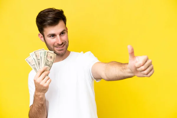 Junger Kaukasischer Mann Nimmt Viel Geld Isoliert Auf Gelbem Hintergrund — Stockfoto