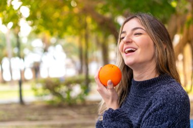 Genç, güzel Romen kadın elinde portakal tutuyor.