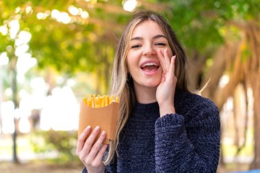 Genç, güzel Romen kadın, elinde kızarmış cipslerle, ağzı açık bağırıyor.