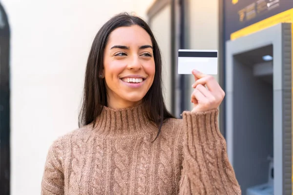 幸せな表情で屋外でクレジットカードを保持している若い女性 — ストック写真