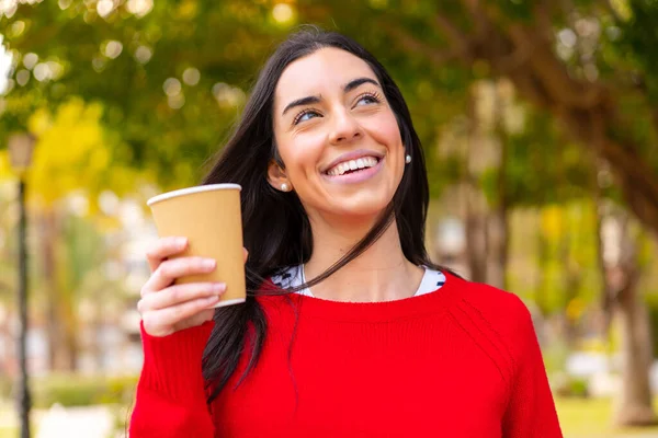 年轻女子一边微笑着一边举杯 目不转睛地看着外面的咖啡 — 图库照片