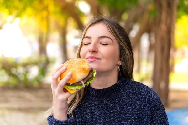 Młoda Ładna Rumunka Trzyma Hamburgera Świeżym Powietrzu — Zdjęcie stockowe