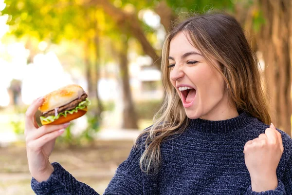 Młoda Ładna Rumunka Trzyma Hamburgera Świeżym Powietrzu Świętując Zwycięstwo — Zdjęcie stockowe