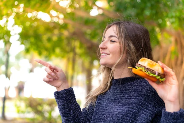 Jeune Jolie Roumaine Tenant Hamburger Extérieur Pointant Vers Côté Pour — Photo
