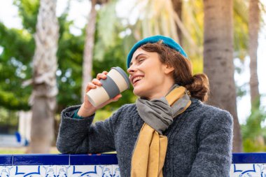 Esmer bir kadın açık havada kahve ikram ediyor.