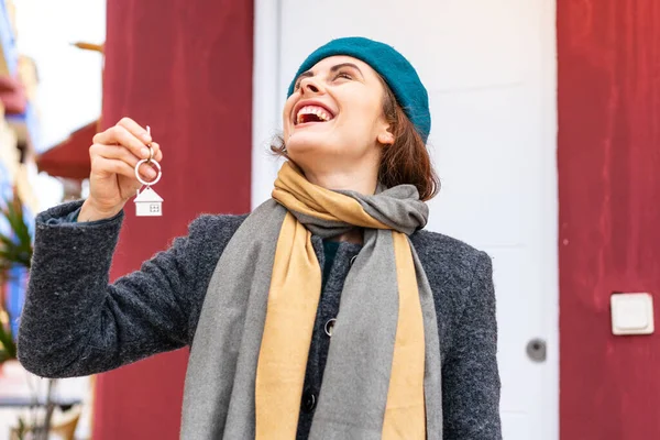 stock image Brunette woman holding home keys at outdoors looking up while smiling