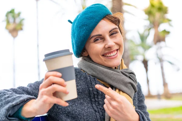 布鲁内特的女人在户外拿起咖啡指着咖啡 — 图库照片