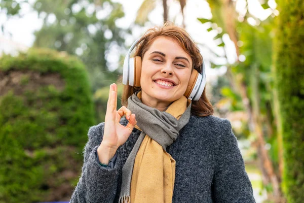 Μελαχρινή Γυναίκα Ακούγοντας Μουσική Ακουστικά Εξωτερικούς Χώρους Δείχνει Υπογράψει Δάχτυλα — Φωτογραφία Αρχείου