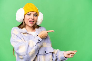 Sarışın genç bir kadın, izole edilmiş krom üzerine kışlık manşetler takıyor.